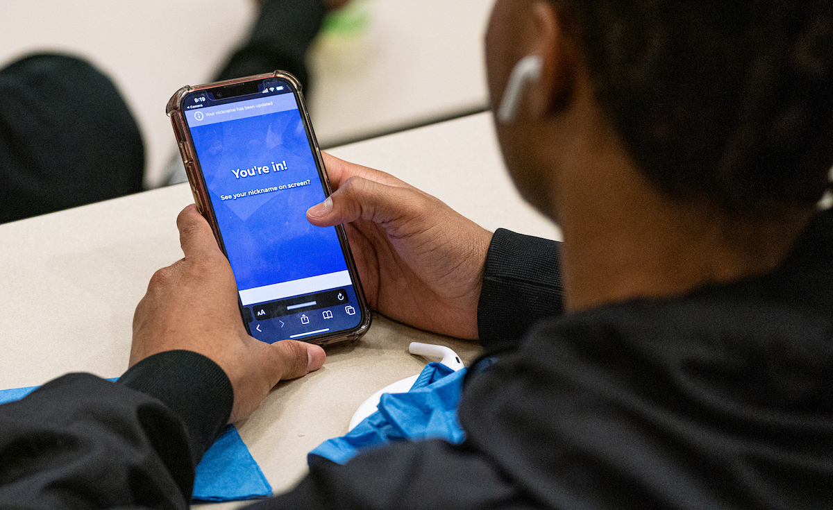 A person holds a smartphone with a screen displaying "You're in!" while sitting at a table, ready to embark on a virtual tour.